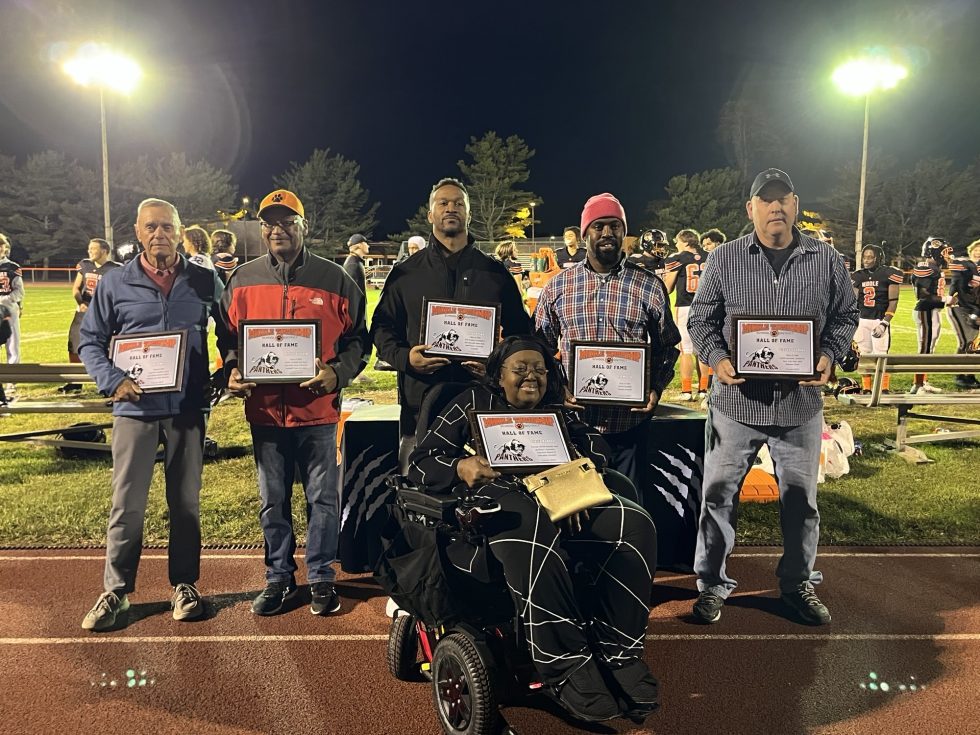 MTHS Hall of Fame members standing on the football field with their certificates.